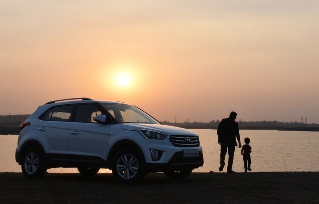 car with parent and child with sunset